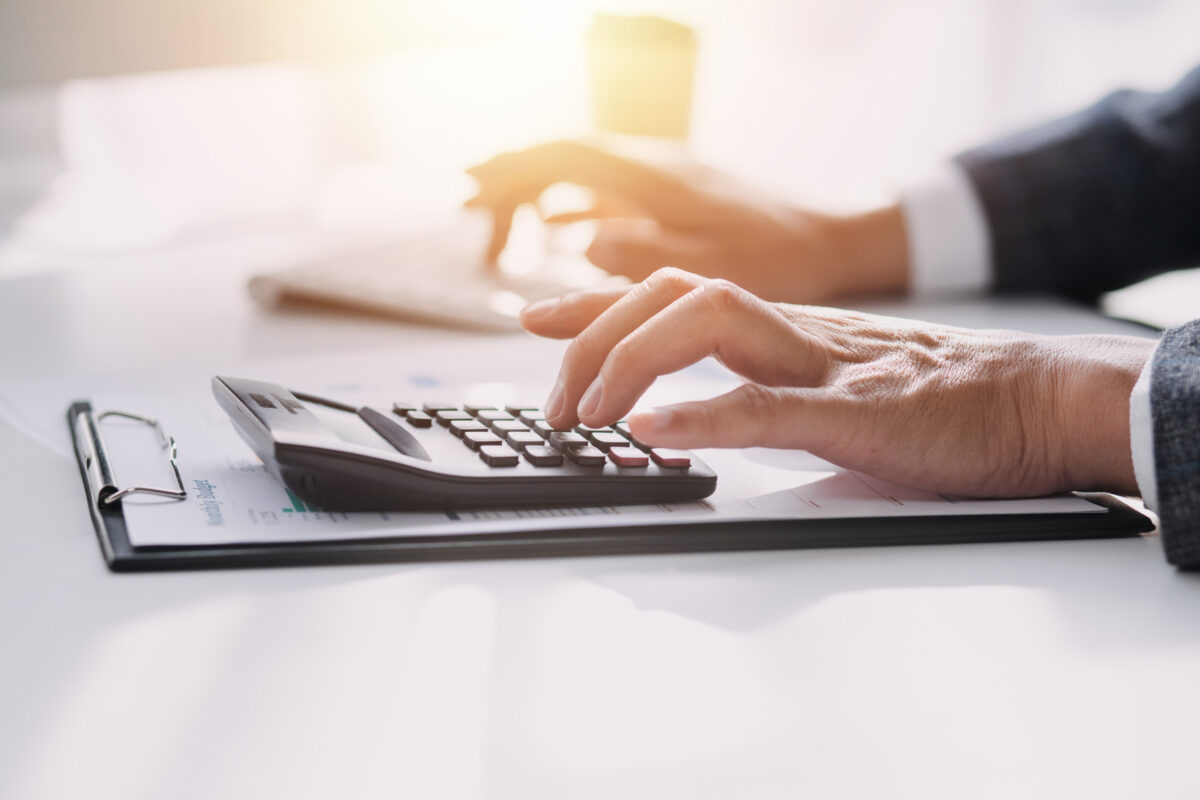 Asian Business woman using calculator and laptop for doing math