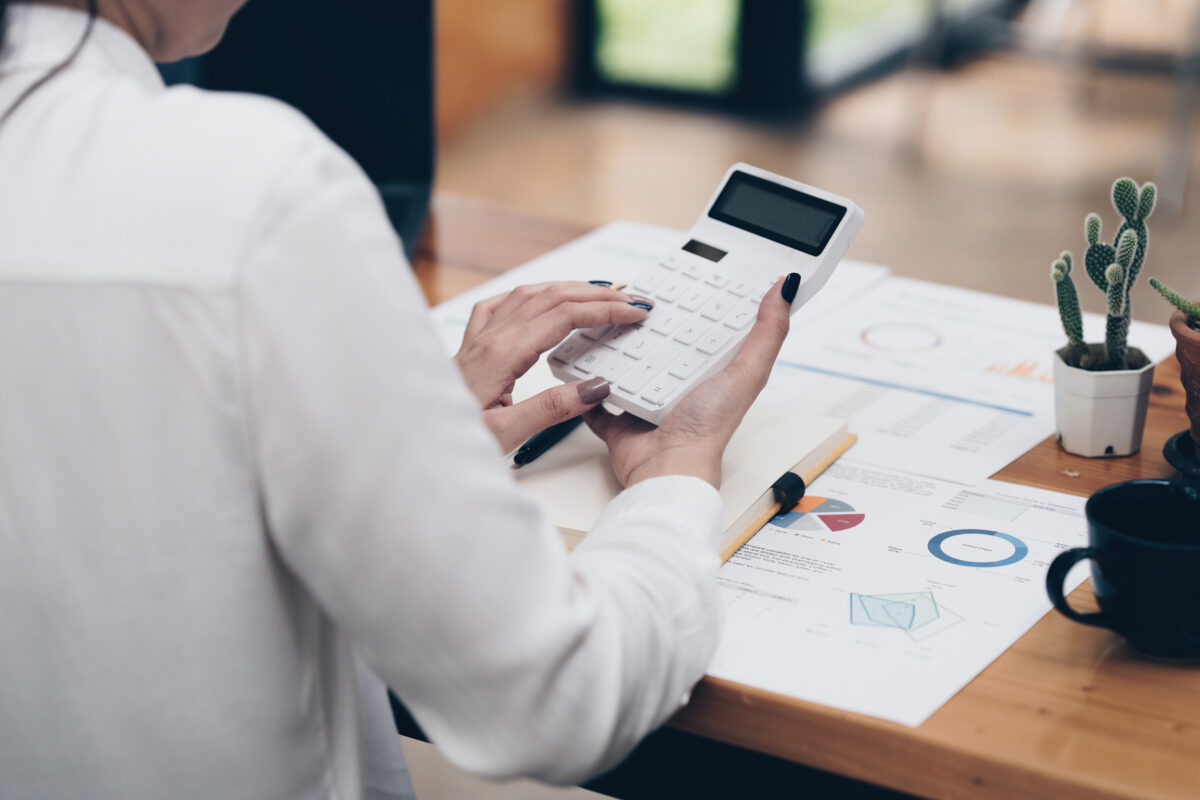 Asian Business Woman or Accountant do math and analyze with calculator and paperwork on desk, account, audit and saving concept